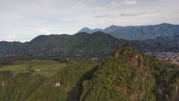 View of lush green hills and mountains around Lake Atitlán, Guatemala, showcasing vibrant landscapes under a blue sky.