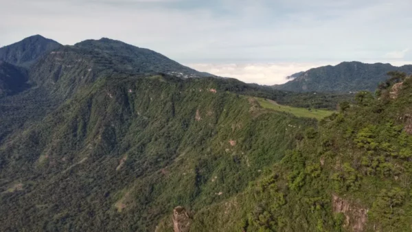 Lush green mountains stretch across the horizon above Lake Atitlán, with a serene mist hovering over the valley below.