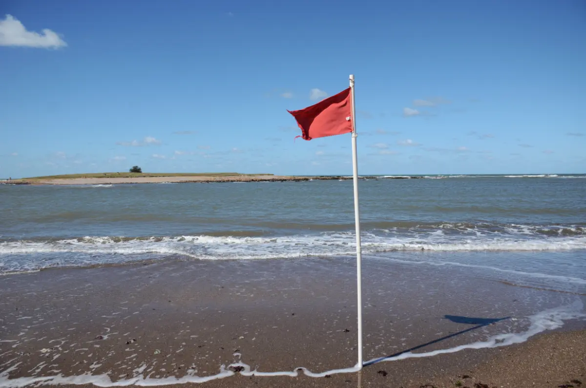 a red flag and Isla La Tuna across the strait from Bahía Chica
