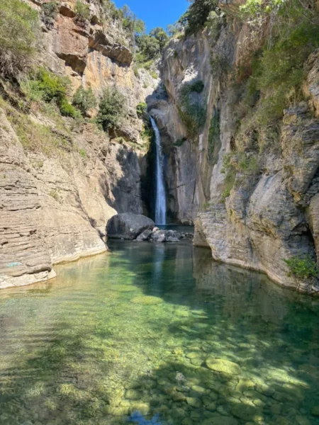 Waterfall cascading into an emerald pool at Manikiatis Waterfall in Central Evia