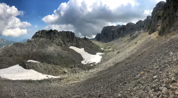 Breathtaking view of Mount Xerovouni in Euboea, Greece, featuring rocky terrain and patches of snow under a cloudy sky.