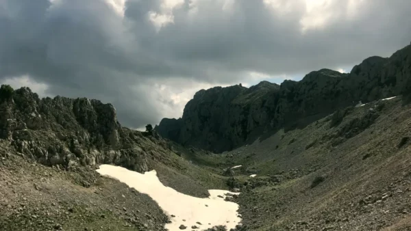Mount Xerovouni showcases rocky terrain and patches of snow under dramatic clouds in Euboea, Greece.