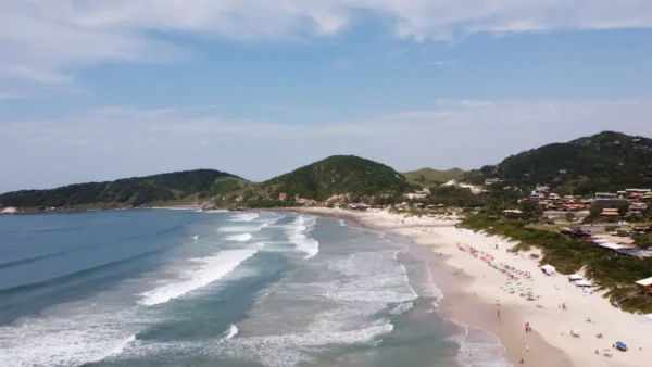 Praia do Rosa showcases golden sands and gentle waves, framed by lush hills and a serene coastline in Santa Catarina, Brazil.