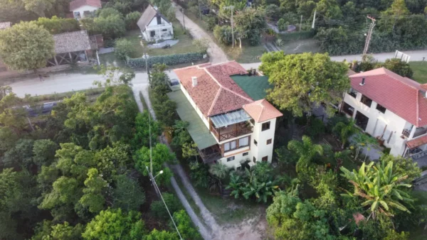 Praia do Rosa features lush greenery surrounding a charming multi-level house with a red-tiled roof in Santa Catarina, Brazil.