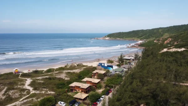 Praia do Rosa features golden sands, gentle waves, and lush greenery lining the coastline of Santa Catarina, Brazil.