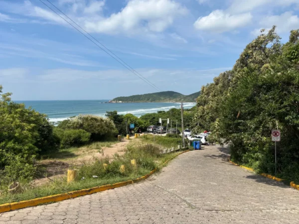 Praia do Rosa features a scenic ocean view with lush greenery lining the road, leading to the sandy beach in Santa Catarina, Brazil.