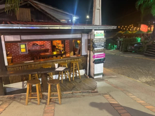 Cozy bar with wooden stools and a warm atmosphere at Praia do Rosa, Santa Catarina, Brazil, illuminated by soft lights.