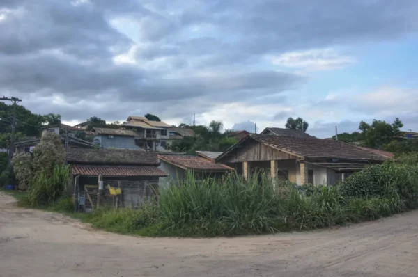 Abandoned houses surrounded by lush greenery and overcast skies in Praia do Rosa, Santa Catarina, Brazil.