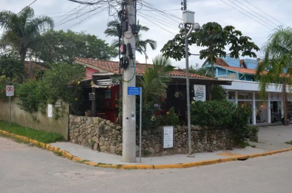 Charming café with stone walls and tropical plants at Praia do Rosa, Santa Catarina, Brazil, surrounded by a vibrant street scene.