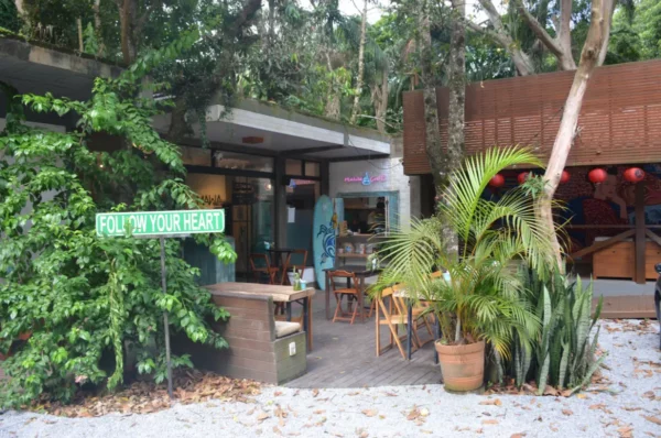 Colorful outdoor café surrounded by lush greenery at Praia do Rosa, Santa Catarina, Brazil, inviting visitors to relax and enjoy.