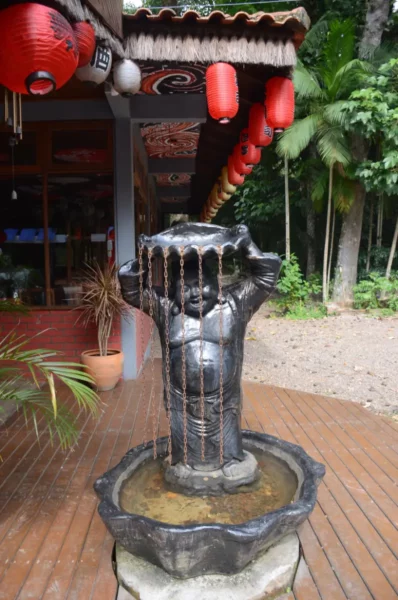 statue of buddha carrying a shell with hanging chains on his his head below chinise lamps