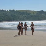 brazilian girls walking on sand at praia vermelha near praia do rosa in santa catarina