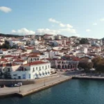 Aerial view of Pylos harbor in southwestern Greece, showing the natural bay, red-roofed town, marina, and surrounding hills along the Messinian coast.