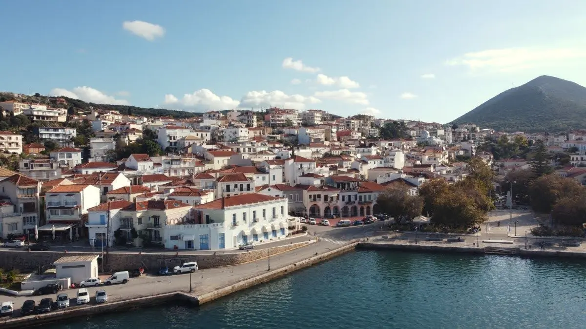 Aerial view of Pylos harbor in southwestern Greece, showing the natural bay, red-roofed town, marina, and surrounding hills along the Messinian coast.