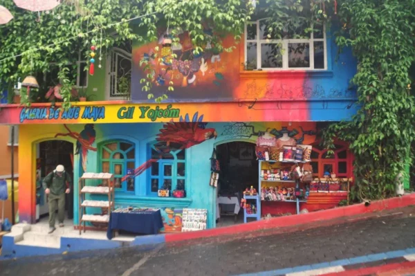 Colorful facade of a weaving cooperative in San Juan La Laguna, Guatemala, painted with murals and displaying handmade textiles and crafts for sale.