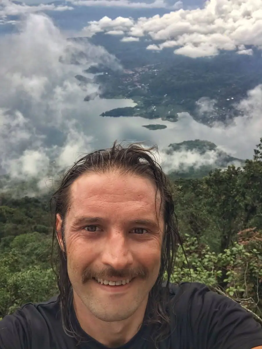 Selfie on the top of Volcán San Pedro, with Lake Atitlán, clouds, and villages spread out below.