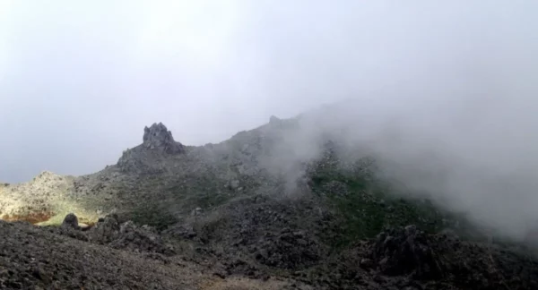 Misty rocky landscape at Xerovouni, with rugged terrain and soft light illuminating a distant peak.
