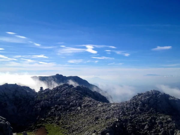 Stunning view from Xerovouni, showcasing rocky peaks and a misty landscape under a bright blue sky.