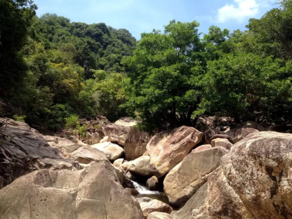 Breathtaking Ba Ho Waterfalls showcase lush greenery and smooth, natural rocks alongside a tranquil stream.