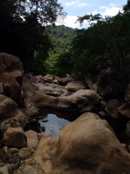 Breathtaking rock formations and serene waters highlight the natural beauty of Ba Ho Waterfalls, surrounded by lush greenery.
