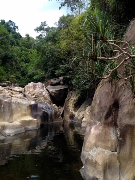 Serene ba-ho waterfalls view with lush greenery and smooth rock formations reflected in calm waters.