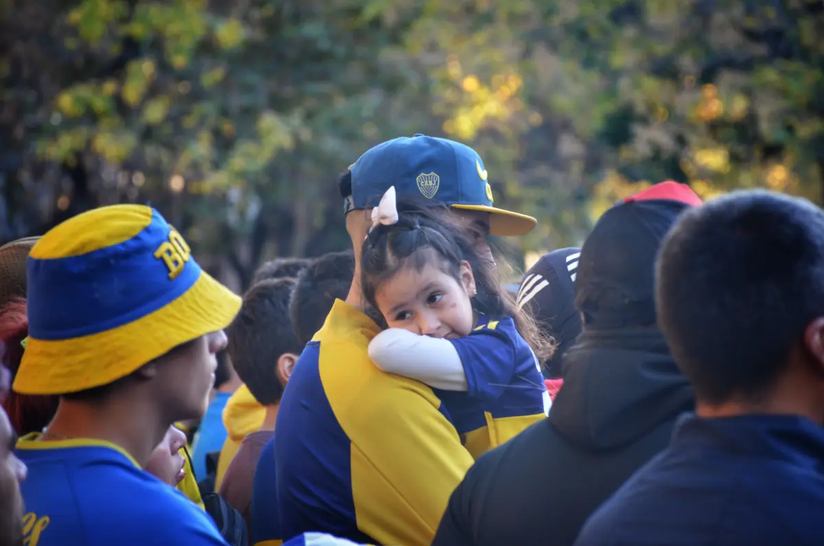 fan of boca juniors holding little daughter on shoulder in buenos aires