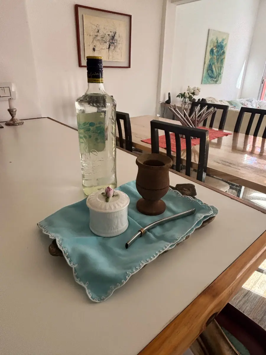 cup of argentine mate with straw and bottle of water on table corner