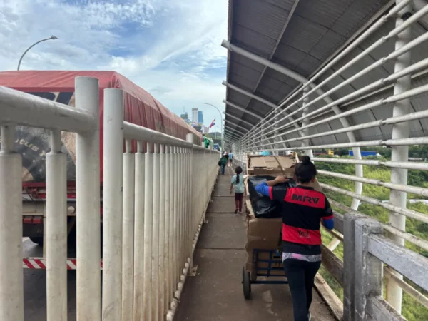 Mulher empurrando um carrinho carregado com caixas de papelão pela passarela da Ponte da Amizade entre Brasil e Paraguai