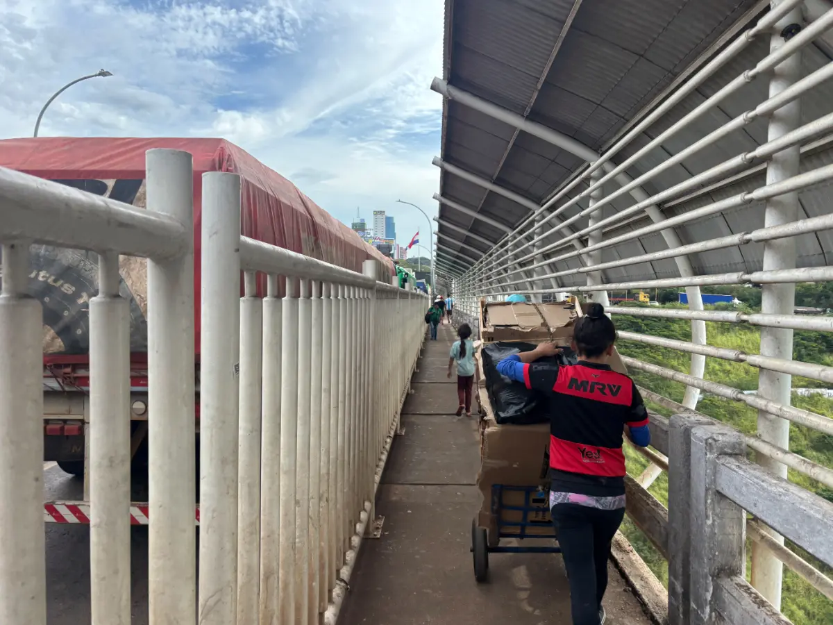 Mulher empurrando um carrinho carregado com caixas de papelão pela passarela da Ponte da Amizade entre Brasil e Paraguai
