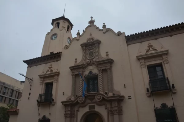Colonial architecture and clock tower reflect Cordoba's historic charm in Argentina. Soft gray skies enhance the scene.