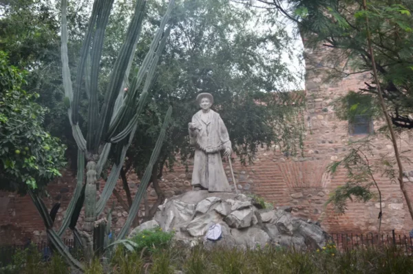 Statue surrounded by lush greenery and cacti in Córdoba, Argentina, capturing cultural heritage and natural beauty.