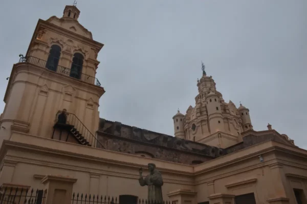 Historic architecture with ornate towers and a statue, set against a cloudy sky in Córdoba, Argentina.