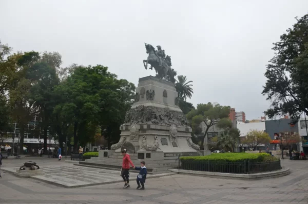 Monument to General San Martín surrounded by lush greenery in Córdoba, Argentina, with visitors exploring the plaza.