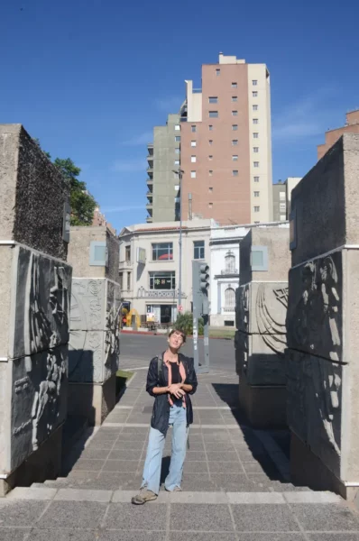 Modern buildings and textured stone sculptures characterize the urban landscape of Córdoba, Argentina, under a clear blue sky.