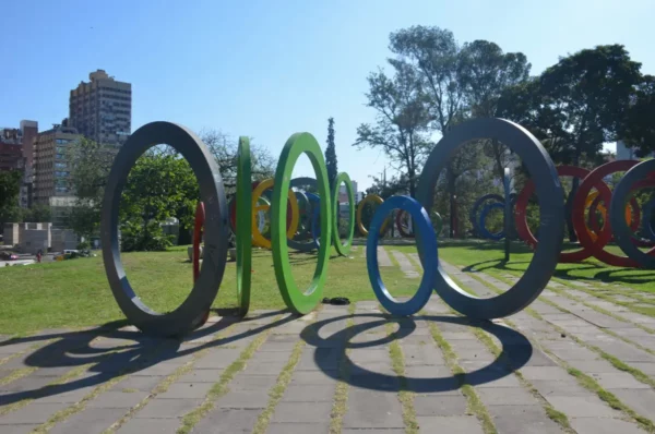 Colorful circular sculptures create an engaging layout in Córdoba, Argentina, with green spaces and city buildings in the background.