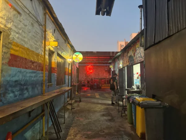Vibrant alleyway in Córdoba, Argentina, featuring colorful walls, neon lights, and a lively atmosphere at dusk.