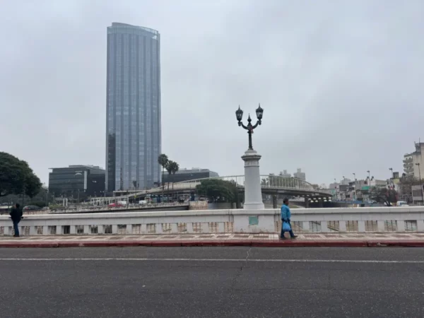 Modern skyscraper contrasts with historic architecture along the boulevard in Córdoba, Argentina, under a cloudy sky.