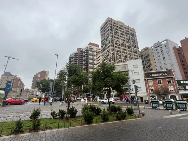 Modern high-rise buildings and lush greenery in Córdoba, Argentina, showcase a bustling urban atmosphere under a cloudy sky.