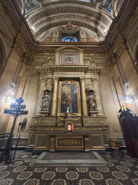 Elaborate altar with golden details and religious statues inside a historic church in Córdoba, Argentina. Richly decorated architectural features.