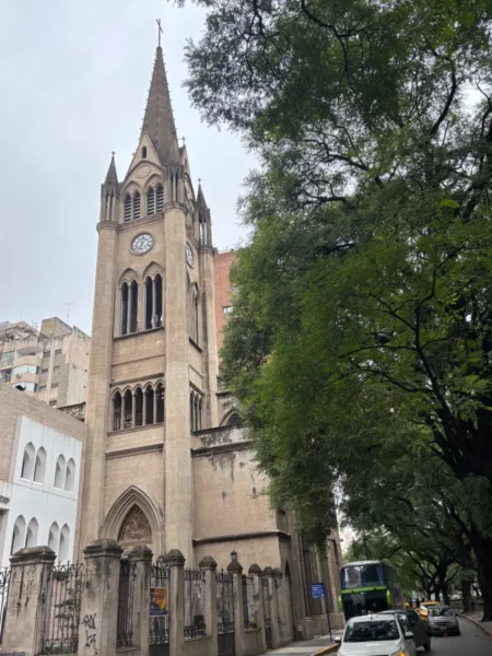Beautiful architecture and lush trees line the street near Cordoba's historic church in Argentina, showcasing a blend of nature and culture.