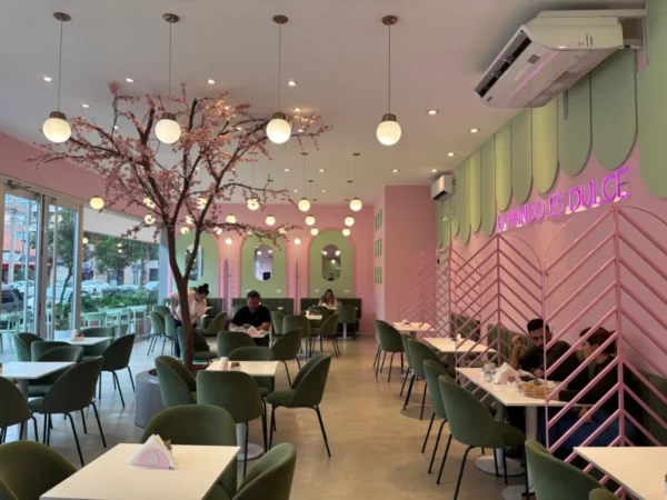 Charming pink and green cafe interior in Cordoba, Argentina, featuring stylish furniture and decorative lighting.