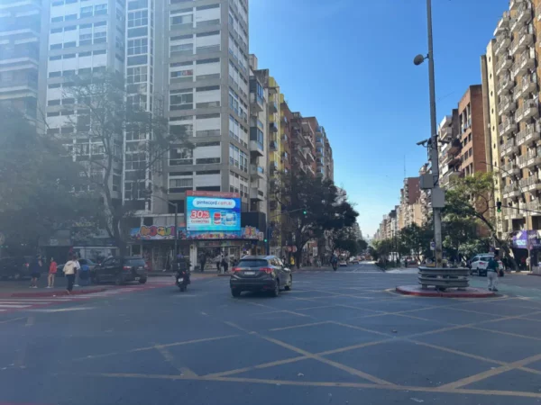 Busy urban street with modern buildings and a clear sky in Córdoba, Argentina, showcasing daily city life and traffic.