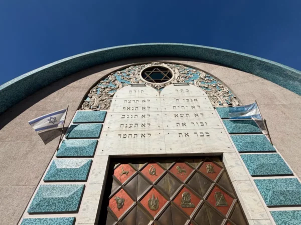 Beautiful blue and turquoise facade of a synagogue, featuring a Star of David and flags, set against a clear sky in Córdoba, Argentina.