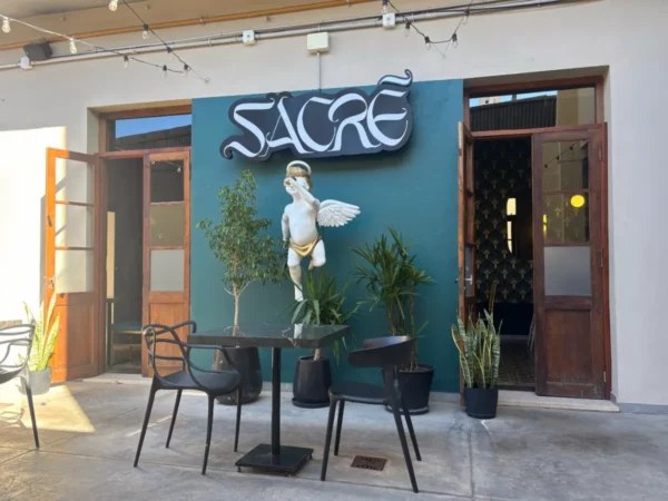 Sacre café entrance features a whimsical angel statue and greenery in Córdoba, Argentina, inviting visitors to enjoy the vibrant atmosphere.