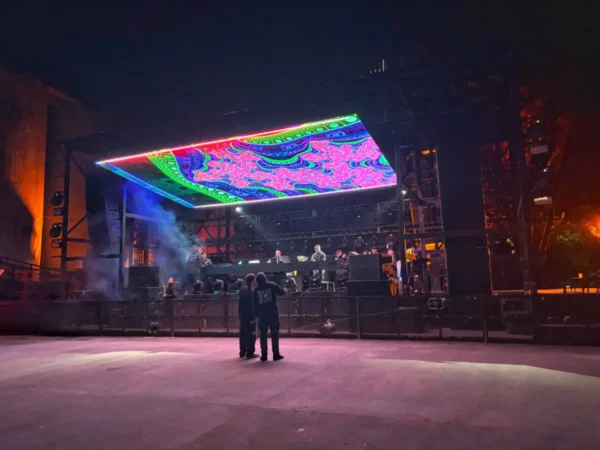 Vibrant stage with colorful lighting and digital display in Córdoba, Argentina, hosting a lively outdoor event at night.