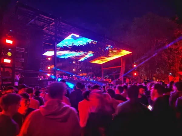 Vibrant night scene in Cordoba, Argentina, featuring a lively crowd at a music festival with colorful lights and a dynamic stage display.