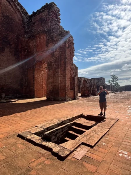 man standing before a Stairway to a basement on the ground of the main church in la santisima trinidad de parana jesuit ruins in paraguay