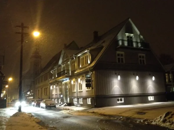 Charming buildings illuminated by streetlights along a snowy road in Parnu at night, creating a cozy winter atmosphere.
