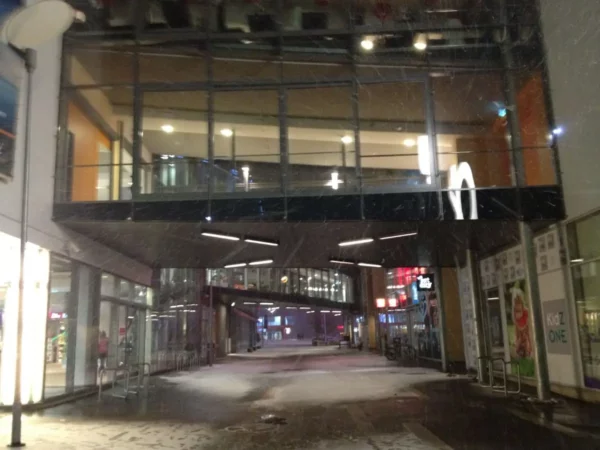 Modern architecture and a bustling street scene with a McDonald's in Pärnu, illuminated amidst evening snow.