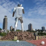 giant metallic statue of a man with spear with buildings in the background in posadas, argentina